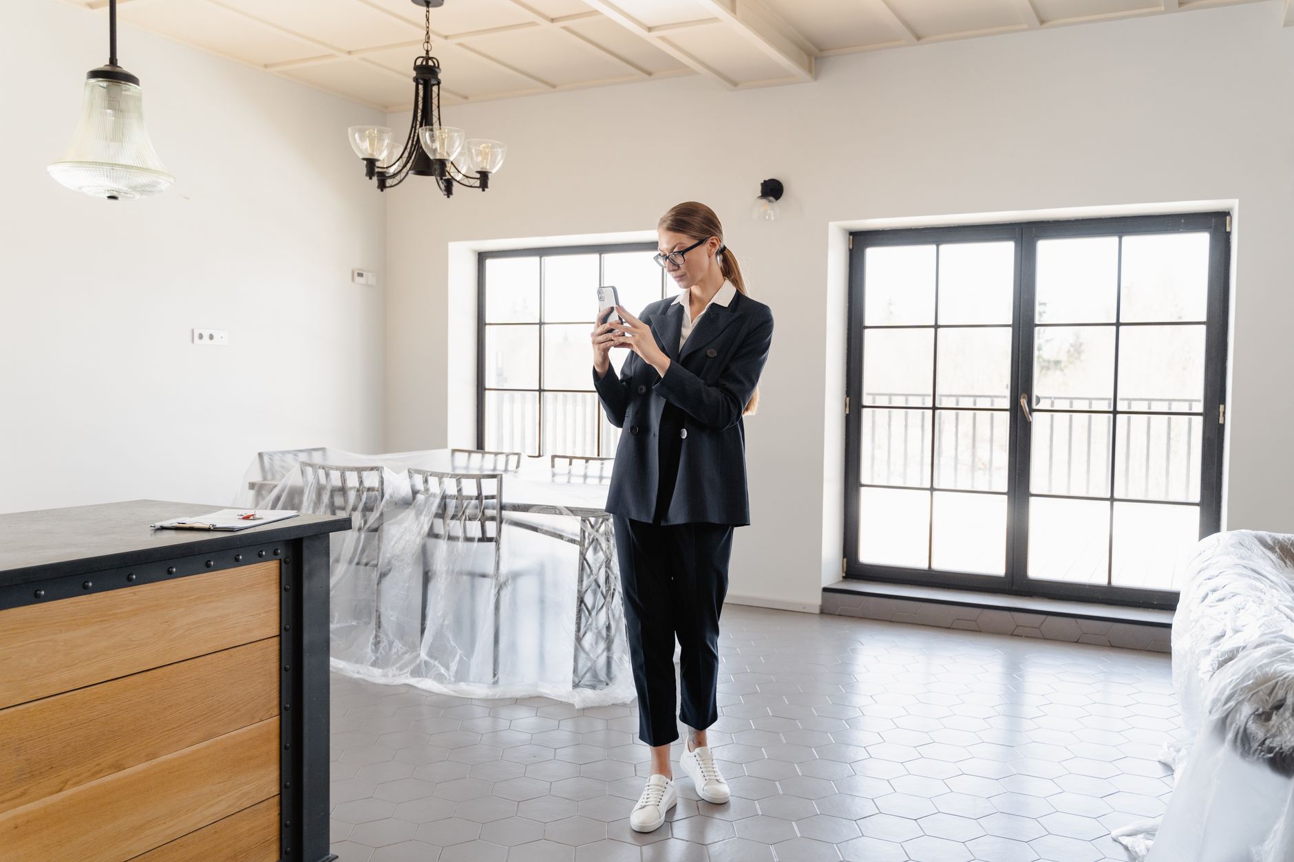 Real estate agent checking a smartphone dashboard while standing in a home during an open house