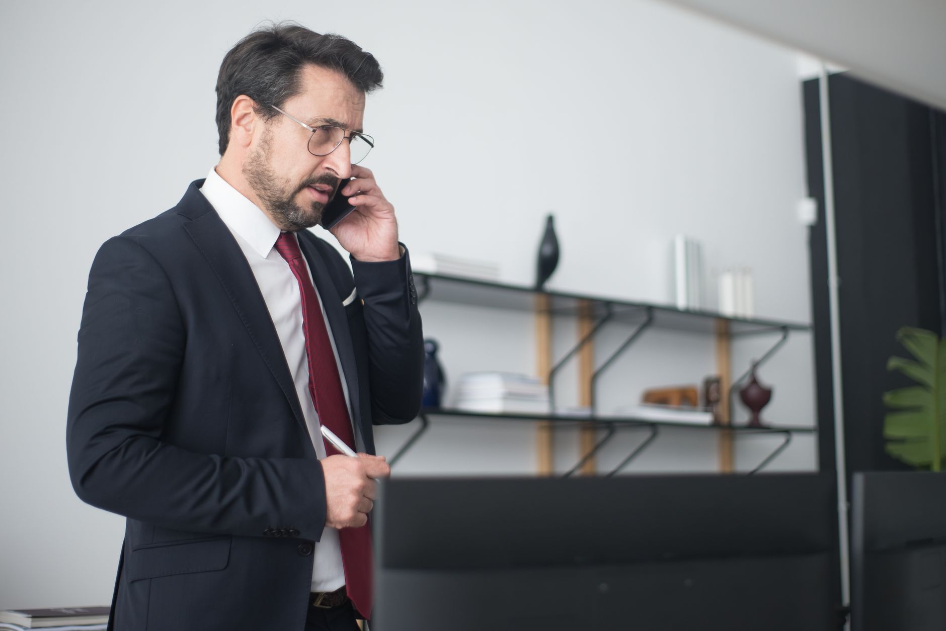 Business professional taking a phone call at a desk while checking call details on a screen